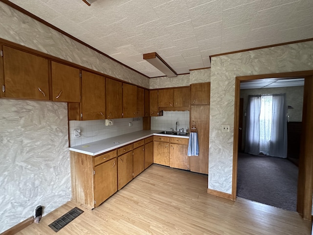2 Lincoln St, Houlton, ME 04730 - kitchen with light countertops, brown cabinets, light wood-style flooring, a sink, and crown molding