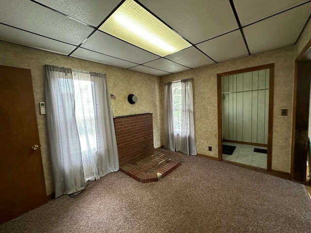 interior space featuring a paneled ceiling, a brick fireplace, and carpet flooring