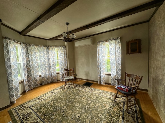 sitting room featuring a notable chandelier, a wall unit AC, beam ceiling, and wood-type flooring