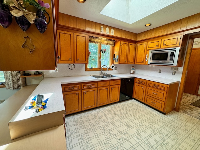 kitchen with sink, stainless steel microwave, and a skylight