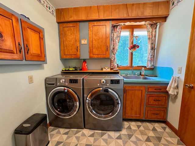 clothes washing area featuring cabinets, sink, and independent washer and dryer