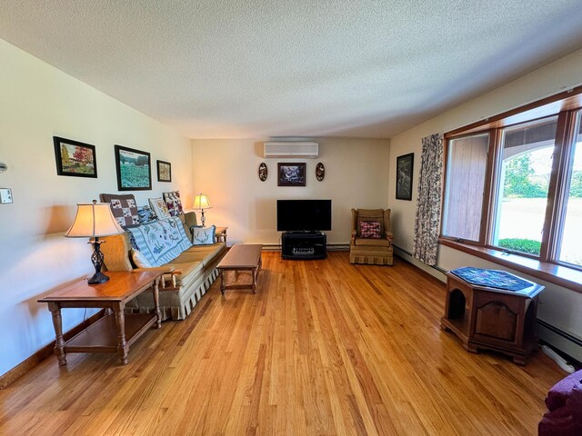 living room featuring light wood-type flooring, a textured ceiling, an AC wall unit, and a baseboard radiator