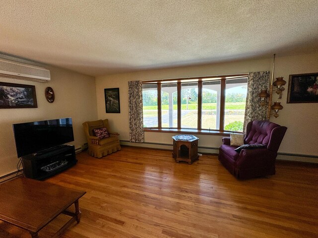 living room featuring a baseboard heating unit, a textured ceiling, hardwood / wood-style floors, and a wall mounted air conditioner