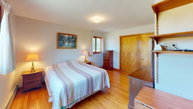 bedroom with light hardwood / wood-style flooring, a baseboard radiator, and a closet