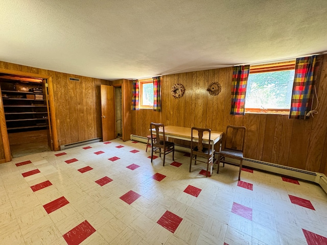 interior space with a baseboard heating unit, a textured ceiling, and wooden walls