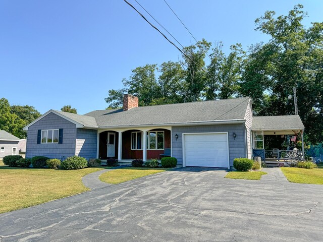 single story home with a garage, covered porch, and a front yard