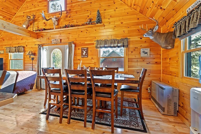 dining space with high vaulted ceiling, wooden ceiling, wood walls, and light wood finished floors