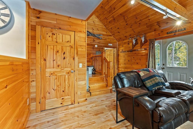 living room featuring light wood-type flooring, track lighting, wood ceiling, vaulted ceiling, and wooden walls