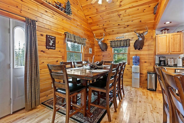 dining space with wooden ceiling, light hardwood / wood-style flooring, vaulted ceiling, and wooden walls