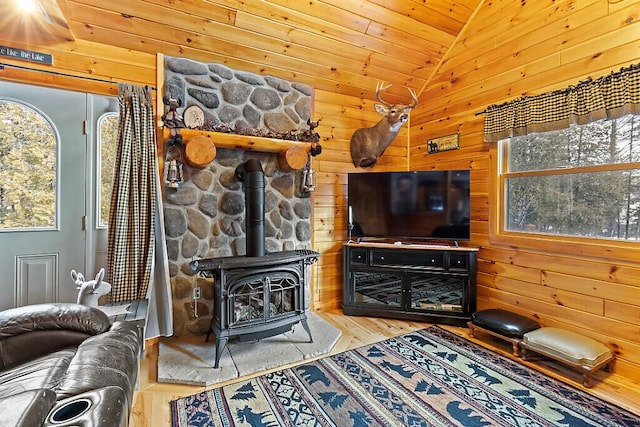 living room with wooden ceiling, a wood stove, wooden walls, vaulted ceiling, and wood-type flooring