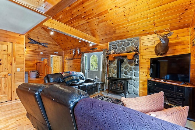 living room with a wood stove, wooden ceiling, wooden walls, vaulted ceiling with beams, and light hardwood / wood-style floors