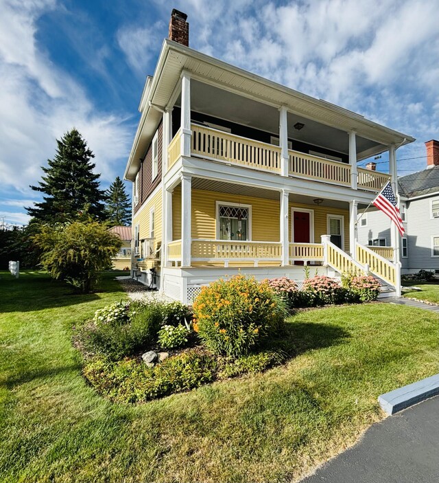 exterior space with a balcony, covered porch, and a front lawn