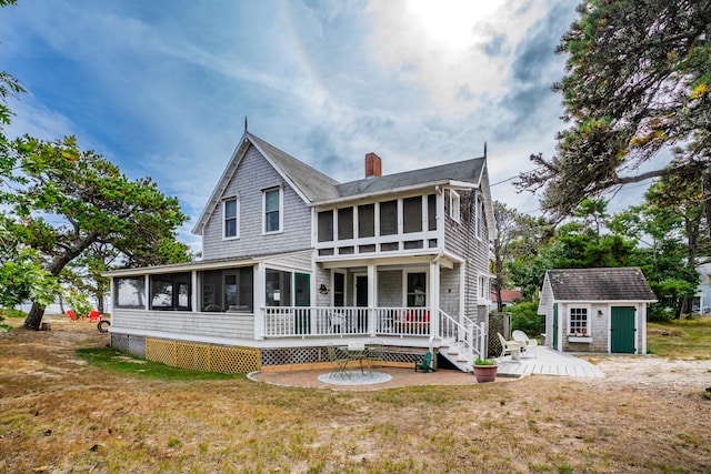 rear view of property featuring a storage shed, a wooden deck, a sunroom, and a yard