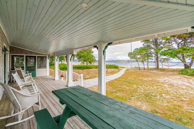 wooden terrace featuring a water view and a yard