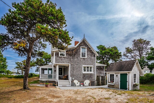 back of house with covered porch and an outdoor structure