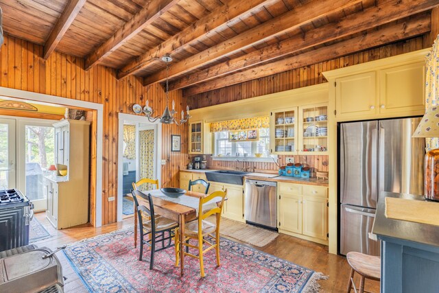 kitchen with wood walls, stainless steel appliances, wooden ceiling, wood-type flooring, and beam ceiling