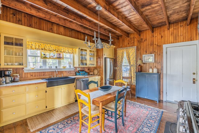 kitchen featuring sink, stainless steel appliances, wood walls, and beam ceiling