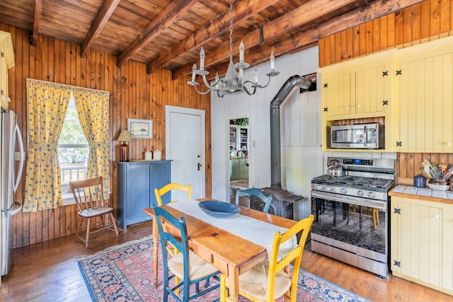 dining room featuring beamed ceiling, a wood stove, wooden ceiling, a notable chandelier, and dark hardwood / wood-style flooring