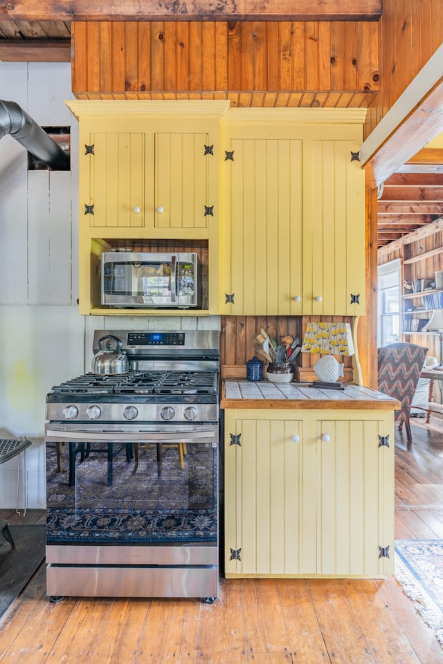 kitchen with tile countertops, light hardwood / wood-style floors, appliances with stainless steel finishes, and tasteful backsplash