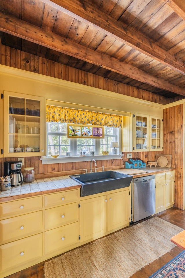 kitchen with beamed ceiling, wood ceiling, stainless steel dishwasher, hardwood / wood-style flooring, and tile counters