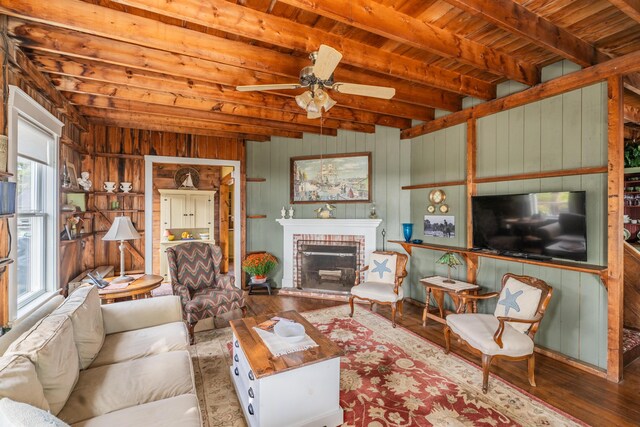 living room with a fireplace, wooden ceiling, wood-type flooring, ceiling fan, and wooden walls