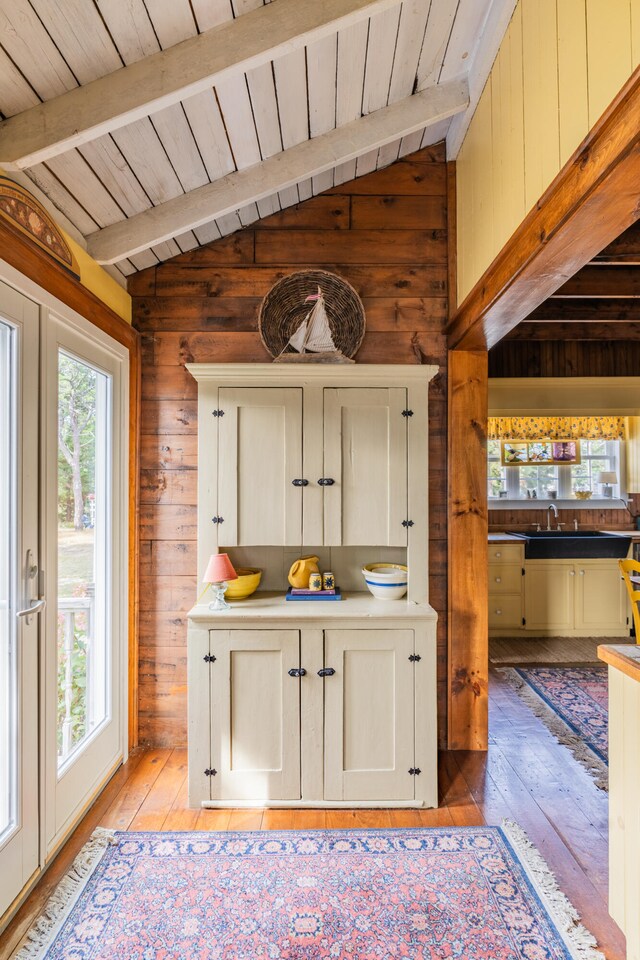 kitchen featuring vaulted ceiling with beams, light wood-type flooring, wood walls, and wood ceiling