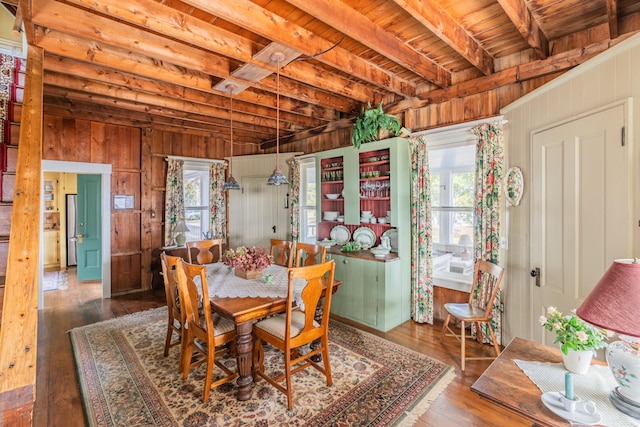 dining area with a healthy amount of sunlight, wood ceiling, wood walls, and dark wood-type flooring