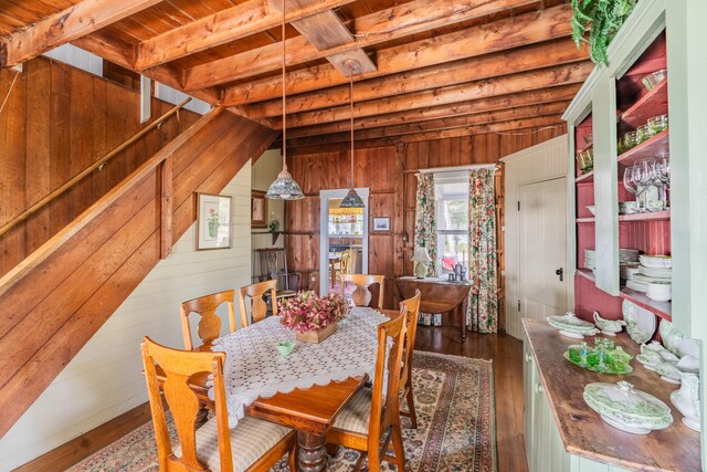 dining area with vaulted ceiling with beams, wood walls, wooden ceiling, and dark wood-type flooring