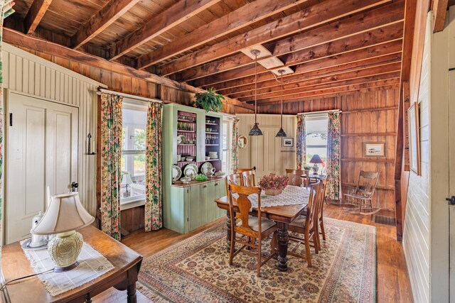 dining room featuring wood-type flooring, wood walls, and a wealth of natural light