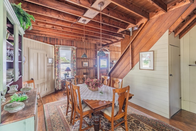 dining space featuring lofted ceiling with beams, wood walls, hardwood / wood-style floors, and wooden ceiling