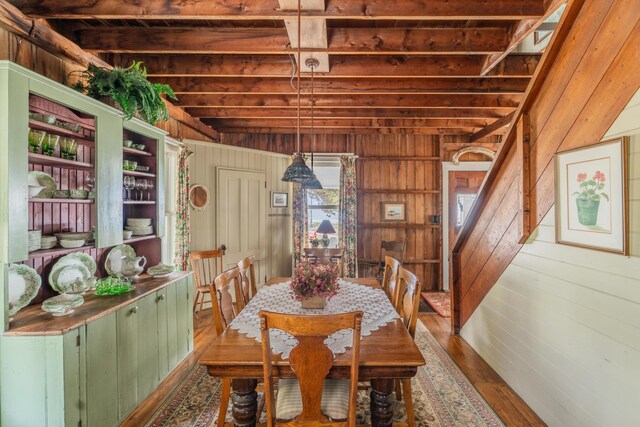 dining area with vaulted ceiling with beams, wood-type flooring, and wooden walls