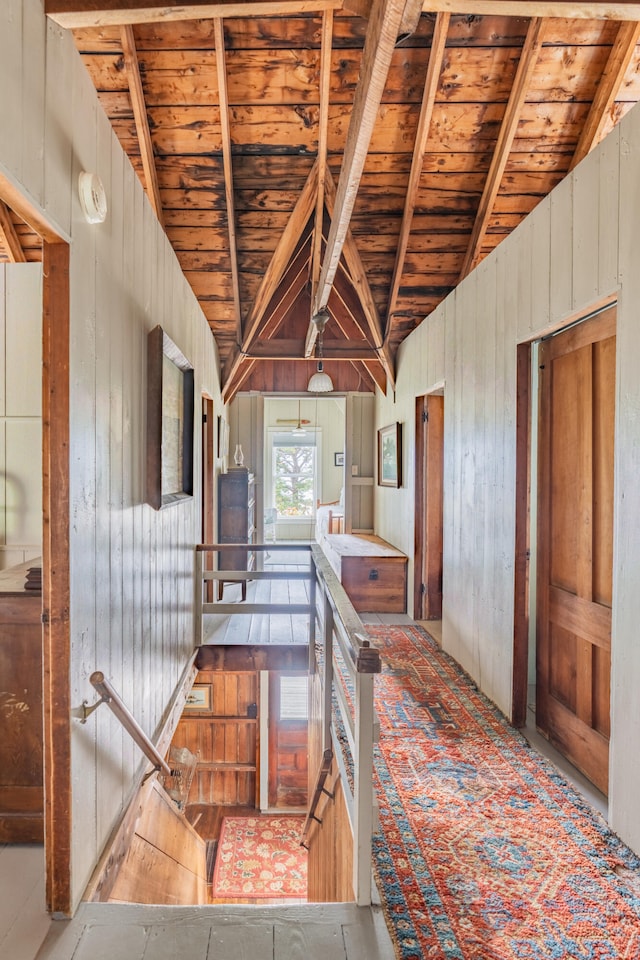 hallway with vaulted ceiling with beams, wooden walls, and wooden ceiling