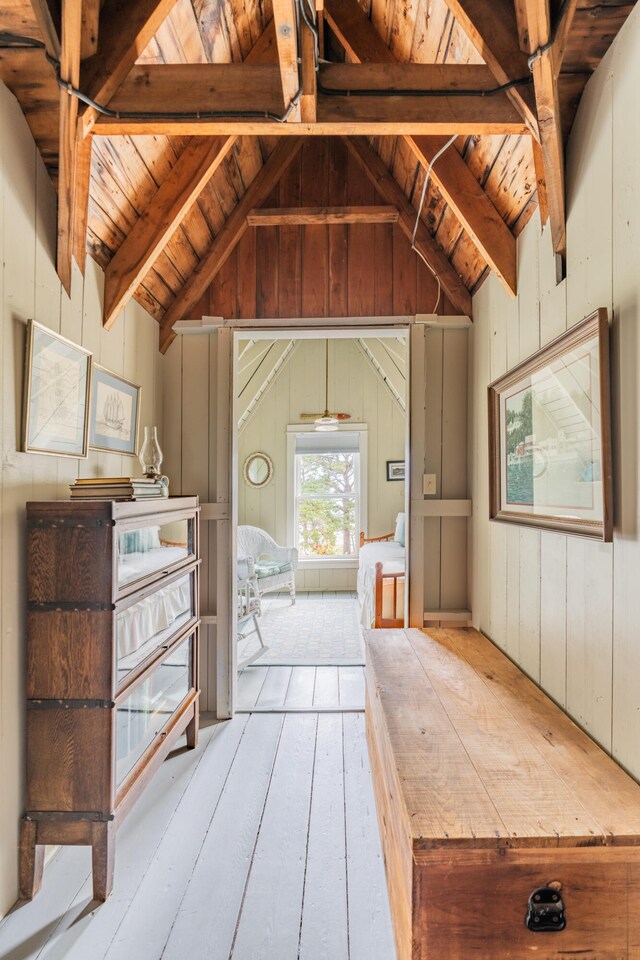 interior space featuring wood walls, wood ceiling, lofted ceiling with beams, and light hardwood / wood-style floors