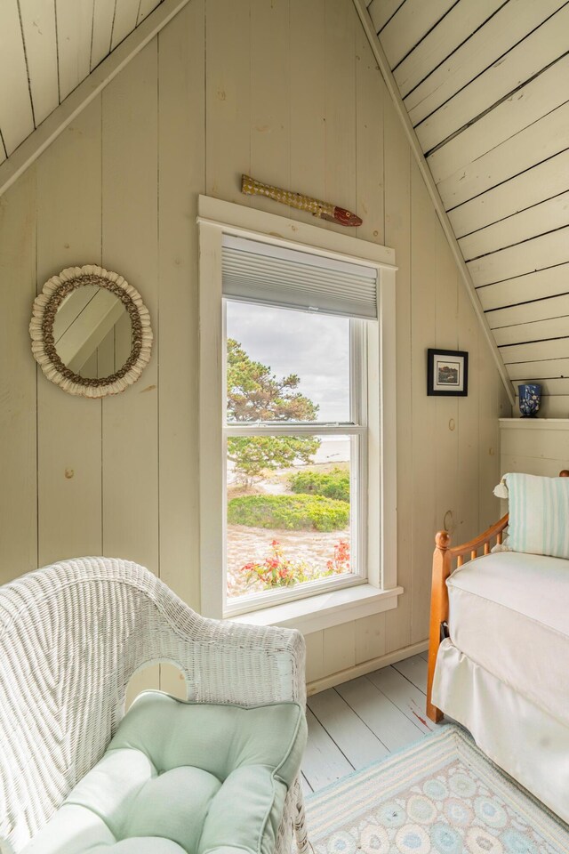 bedroom with light wood-type flooring, lofted ceiling, wood walls, and wooden ceiling