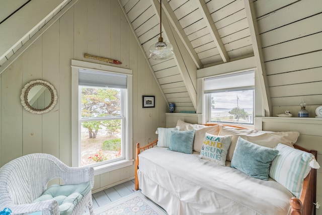 bedroom with multiple windows, wooden walls, and vaulted ceiling