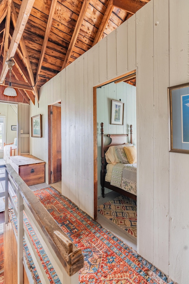 bedroom with lofted ceiling with beams, wood ceiling, and wooden walls