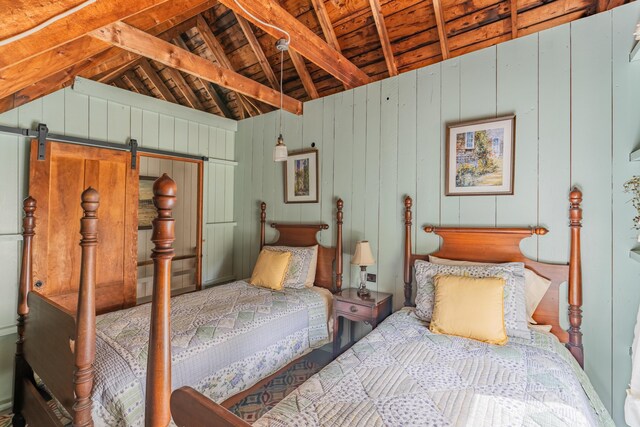 bedroom featuring wooden walls, a barn door, and vaulted ceiling