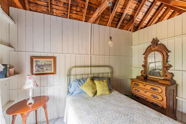 bedroom with wooden walls, vaulted ceiling, and wooden ceiling