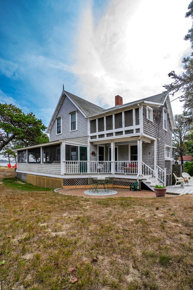 back of house with a lawn and a sunroom