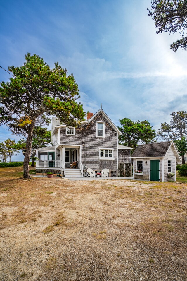 rear view of house featuring covered porch and an outbuilding