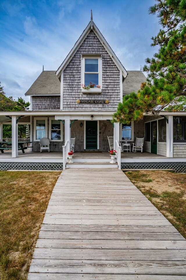 rear view of house featuring a porch and a lawn