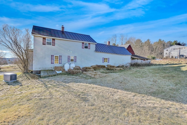 rear view of property featuring a standing seam roof, metal roof, and a chimney