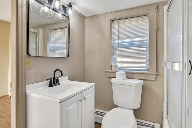 bathroom with wood finished floors, toilet, vanity, and a baseboard radiator