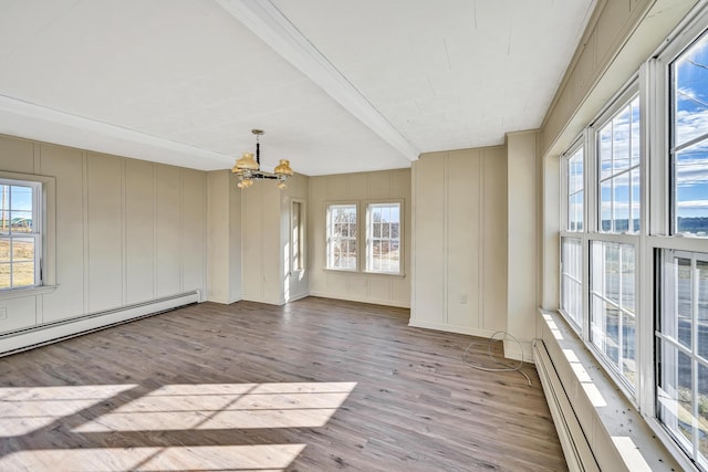 spare room with a baseboard heating unit, a notable chandelier, wood finished floors, and a decorative wall