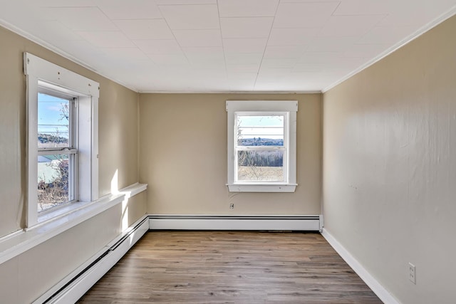 unfurnished room featuring plenty of natural light, wood finished floors, and baseboard heating