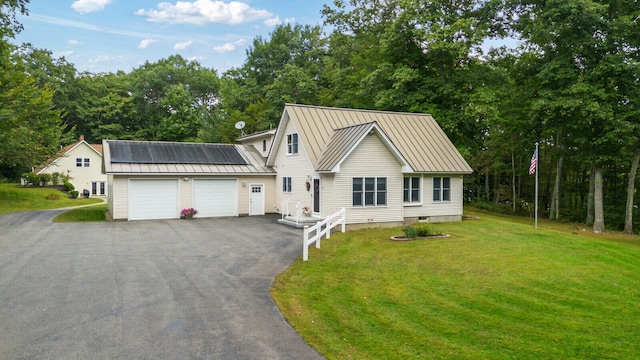 view of front of house featuring a garage, a front lawn, and solar panels