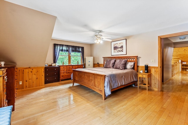 bedroom featuring wood walls, ceiling fan, and light hardwood / wood-style floors