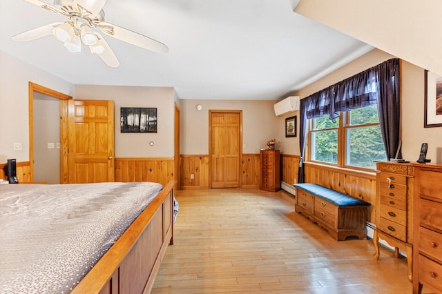 bedroom featuring wooden walls, an AC wall unit, ceiling fan, and light hardwood / wood-style floors