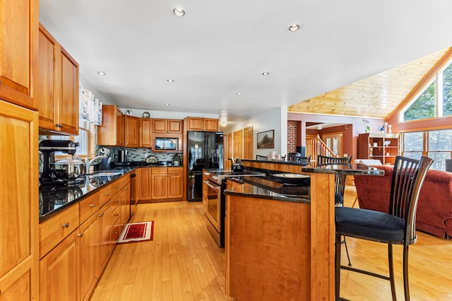 kitchen featuring a kitchen bar, a center island, sink, appliances with stainless steel finishes, and light hardwood / wood-style floors