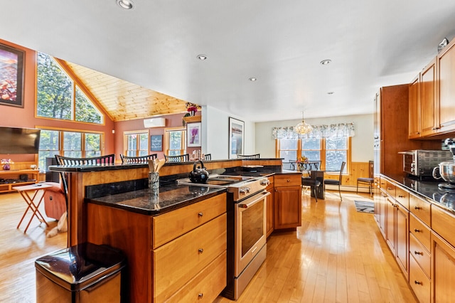 kitchen with light wood-type flooring, a notable chandelier, a kitchen island, lofted ceiling, and high end stove